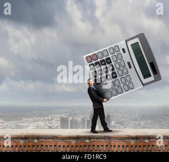 Young businessman carrying huge calculator in hands Stock Photo