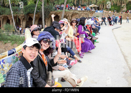 A group of happy oriental people waving at photographer within Parc Guell, Barcelona. A designated World Heritage Site. Stock Photo
