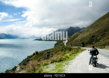 Lake Wakitipu, New Zealand. Motorcycle rider looking at the view on the side of the road. Stock Photo