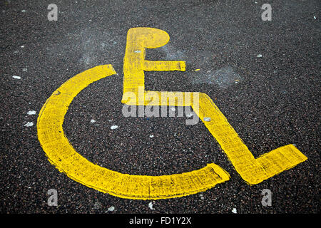 Painted icon of yellow wheelchair in a disable parking bay Stock Photo