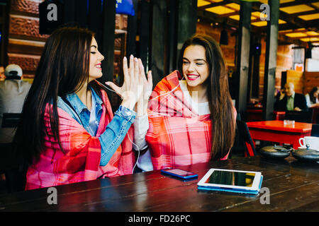 Two young and beautiful girls having fun in cafe Stock Photo