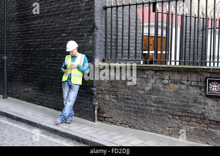 Workman using his mobile phone on a street near Mansion House, London Stock Photo
