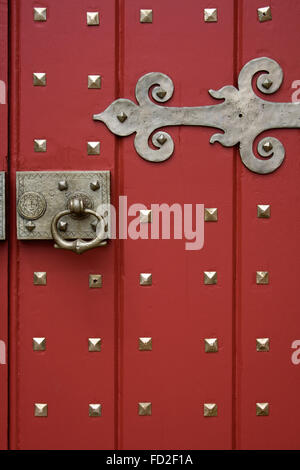 Painted red door with brass hinge and handle Stock Photo
