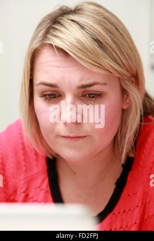 Tired young woman working on her laptop Stock Photo