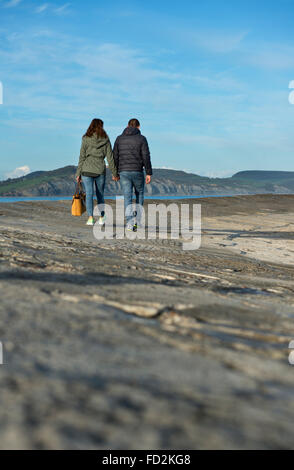 Young couple walking along the Cobb harbour wall at Lyme Regis, Dorset, England, UK Stock Photo