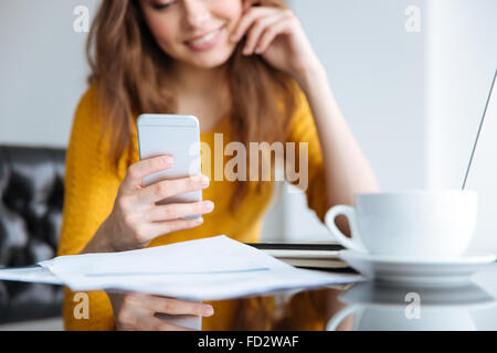 Cropped image of a woman using smartphone at home. Focus on smartphone Stock Photo