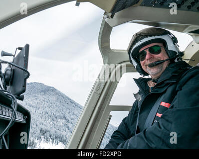 Helicopter pilot flying back country skiers into Selkirk Mountains near remote Mount Carlyle Lodge;  British Columbia; Canada Stock Photo