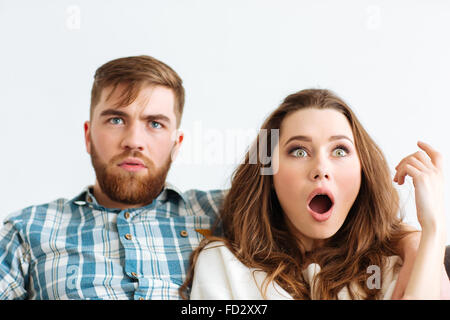 Portrait of a shocked couple looking TV at home Stock Photo