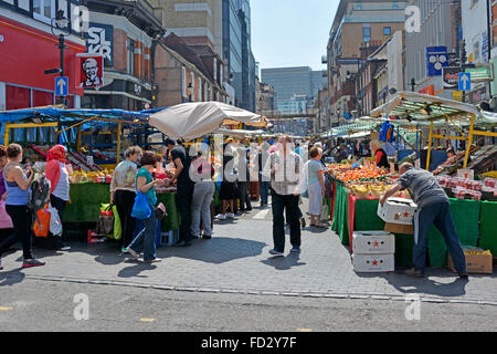 Summer shoppers and stallholder at retail fruit and vegetables stalls in busy Surrey Street market Croydon South London England UK Stock Photo