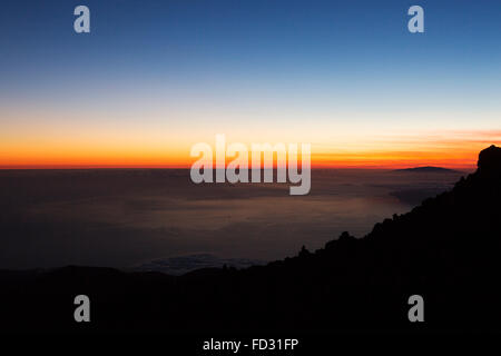 Dusk seen from the slope of Mount Teide in Teide National Park on Tenerife, Spain. Cloud hangs over the Atlantic Ocean. Stock Photo