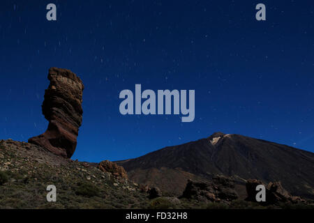 Stars trail in the night sky above Los Roques de Garcia and Mount Teide in Teide National Park on Tenerife, Spain. Stock Photo
