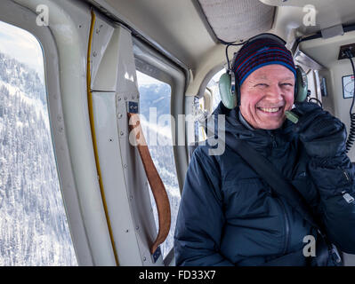 Back country skier flying in helicopter; Selkirk Mountains near remote Mount Carlyle Lodge;  British Columbia; Canada Stock Photo