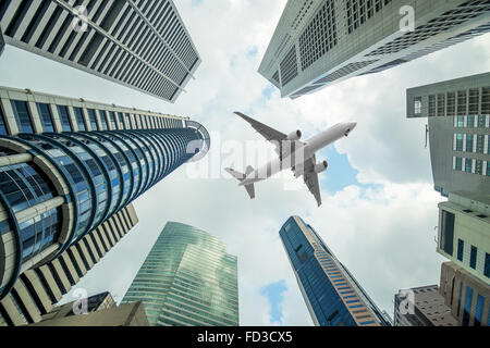 Tall city buildings and a plane flying overhead in morning Stock Photo