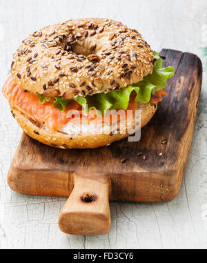 Salmon Bagel Sandwich with cream cheese and grain on blue wooden background Stock Photo