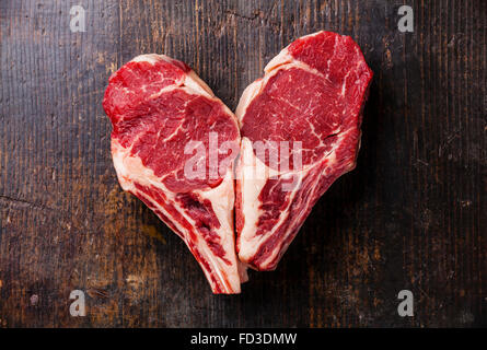 Heart shape Raw meat Ribeye steak entrecote on bone on wooden background Stock Photo