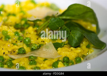 Leek, garden pea and saffron risotto with parmesan cheese. French restaurant prepared cuisine with bright yellow rice Stock Photo