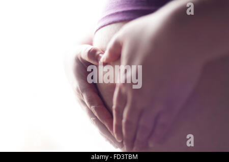 Hands shaping a heart on pregnant mother's baby belly. Heart shaped hands. Stock Photo
