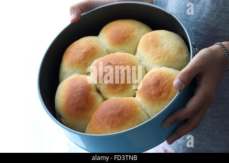 Child hand holding home made baked buns in baking tin Stock Photo