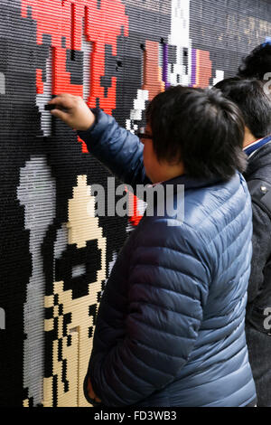 Dragon Quest fans collect blocks from a giant Lego wall mural on January 28, 2016 in Tokyo, Japan. The mural is part of a promotion in Shinjuku Station to celebrate the release of new game Dragon Quest Builders. The 80 meter mural was made with 180,000 Lego blocks and fans were allowed to remove blocks to reveal a secret poster behind. Some blocks contained QR codes allowing fans to access exclusive content. © Rodrigo Reyes Marin/AFLO/Alamy Live News Stock Photo