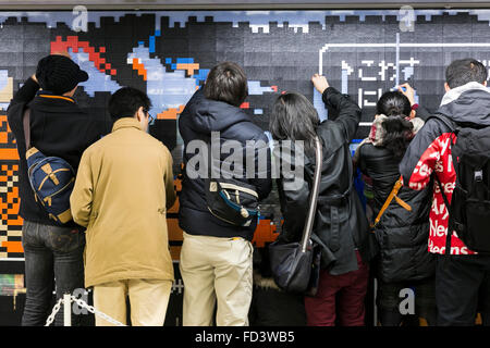 Dragon Quest fans collect blocks from a giant Lego wall mural on January 28, 2016 in Tokyo, Japan. The mural is part of a promotion in Shinjuku Station to celebrate the release of new game Dragon Quest Builders. The 80 meter mural was made with 180,000 Lego blocks and fans were allowed to remove blocks to reveal a secret poster behind. Some blocks contained QR codes allowing fans to access exclusive content. © Rodrigo Reyes Marin/AFLO/Alamy Live News Stock Photo