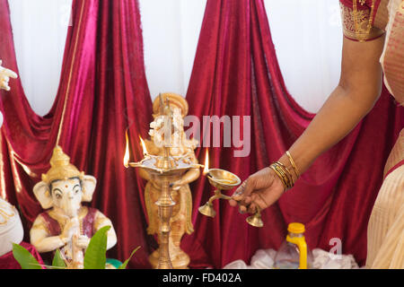 Woman hand lighting up the metal diya. Traditional Indian Hindus religious ceremony. Focus on the oil lamp. India special ritual Stock Photo