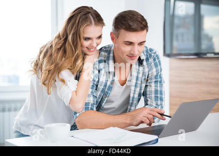 Beautiful couple using laptop and working together at home Stock Photo