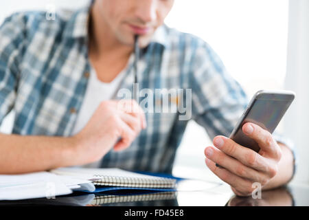 Closeup of mobile phone and notepad used by thoughtful man for counting and paying bills Stock Photo