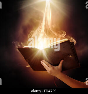 Human hand holding magic book with magic lights Stock Photo