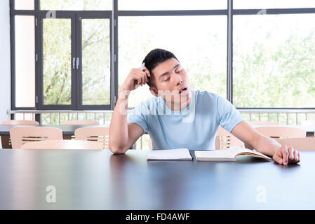 College student falling asleep in library Stock Photo
