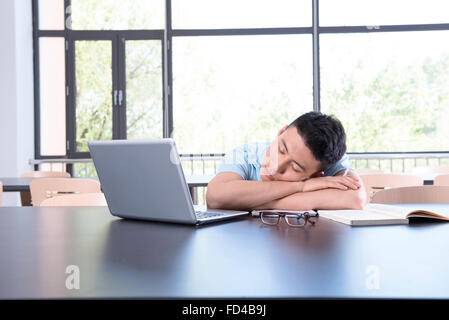College student falling asleep in library Stock Photo