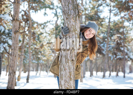 Smiling young woman walking in winter park and looking at camera Stock Photo
