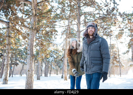 Beautiful happy couple in winter clothes walking outdoors in park Stock Photo