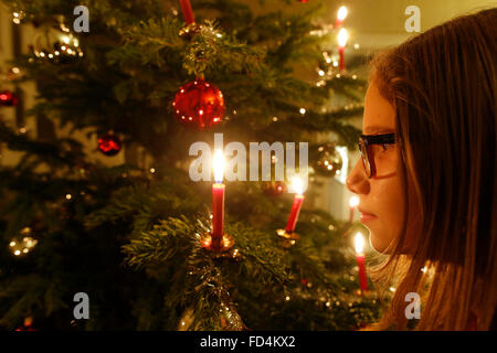 Christmas Tree. Girl looking at the candles Stock Photo - Alamy