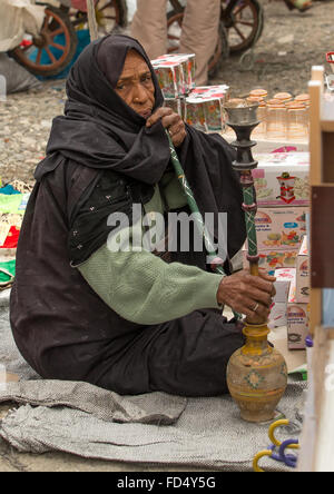 bandari woman smoking pipe at the panjshambe bazar thursday market, Hormozgan, Minab, Iran Stock Photo