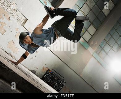 A young man breakdancing on the street of a city, doing a one handed handstand. Stock Photo