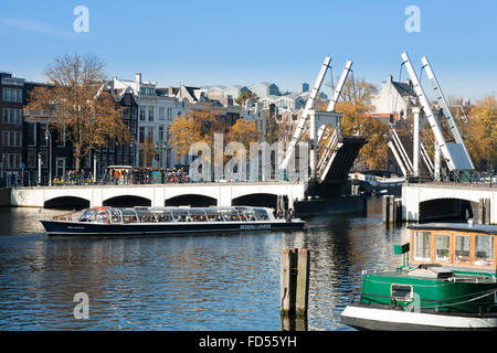 Tourist boat / barge passes under the Magere Brug ('Skinny Bridge') in Dutch capital Amsterdam, The Netherlands, Holland. Stock Photo