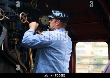 Engineer adjusting valve of steam train LMS Princess Coronation Class 46233 Duchess of Sutherland. Stock Photo
