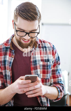 Closeup of smiling handsome bearded man in checkered shirt using mobile phone Stock Photo