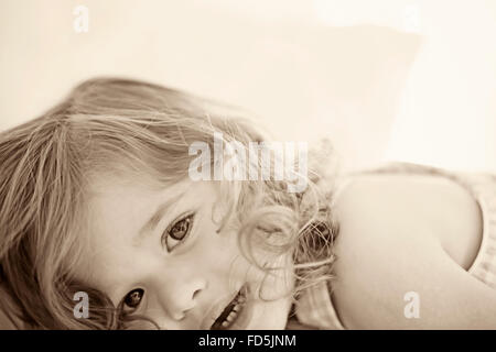 Beautiful toddler girl laying down looking at the camera with an interesting crop. Stock Photo