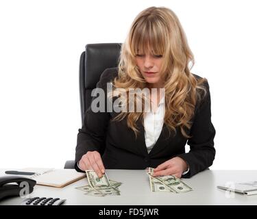 Businesswoman working out her finances sitting at her desk dividing up her money, to cover debts and expenditure. Stock Photo