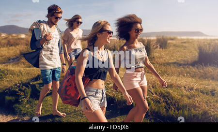 Portrait of group of friends going to on the beach. Mixed group of friends walking on the beach on summer day. Stock Photo