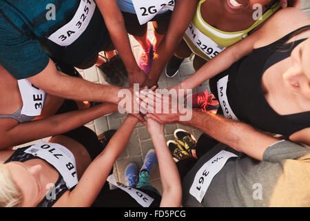 High angle portrait of a sports team standing in a circle with their hands stacked. Team of runners with hands together after co Stock Photo