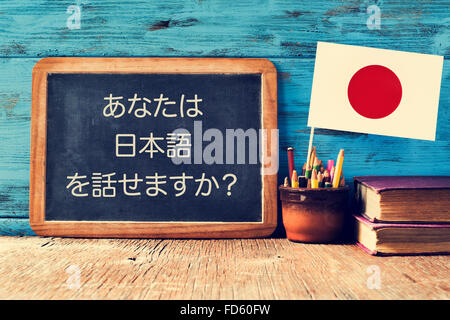 a chalkboard with the question do you speak Japanese? written in Japanese, a pot with pencils, some books and the flag of Japan, Stock Photo