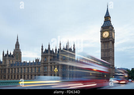 Big Ben and Palace of Westminster in the early morning, red buses passing in London, natural colors and lights