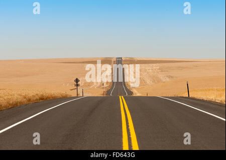 A two lane blacktop highway cuts through wheat fields in The Palouse in Eastern Washington Stock Photo