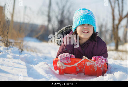 Adorable school aged kid girl in colorful sweater and hat playing in the snow on beauty winter day Stock Photo