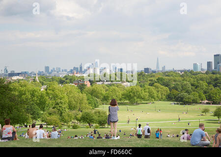 Primrose hill top with London city view and people relaxing in the park, young woman takes pictures Stock Photo