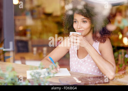 Beautiful woman gazing out a coffee window daydreaming Stock Photo