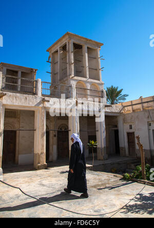 man passing in an old house courtyard with wind towers, Hormozgan, Bandar-e Kong, Iran Stock Photo