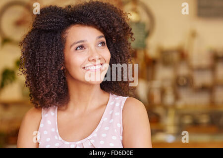 Woman with curly afro dark hair smiling while looking up Stock Photo